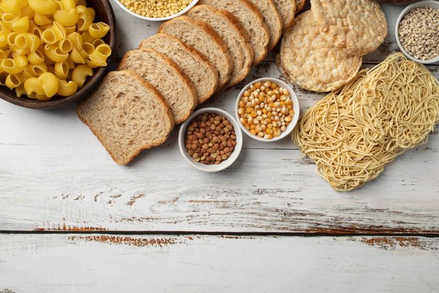 Glutenhaltige Lebensmittel wie Brot, Pasta und Getreide auf einem Holztisch – Thema Glutenintoleranz in der Hausarztpraxis Chur West
